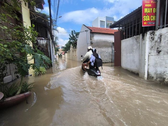 Một người bố mạo hiểm dùng xe máy điện chở con gái rẽ nước đến trường