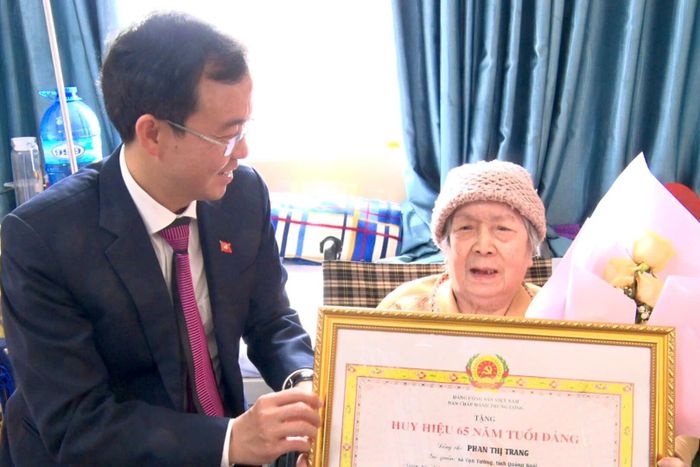 Đồng chí Nguyễn Văn Lộc, Tỉnh uỷ viên, Bí thư Đảng uỷ phường Xuân Hương - Đà Lạt trao tặng Huy hiệu 65 năm tuổi Đảng tại nhà cho đảng viên Phan Thị Trang