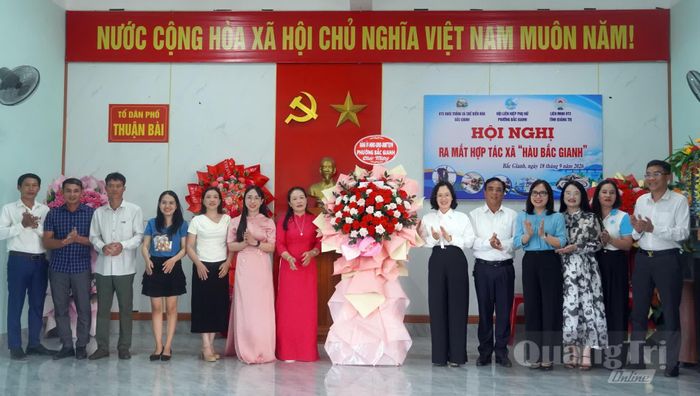 Đại diện lãnh đạo phường Bắc Gianh tặng hoa chúc mừng Hợp tác xã nuôi trồng và chế biến hàu Bắc Gianh - Ảnh: N.M