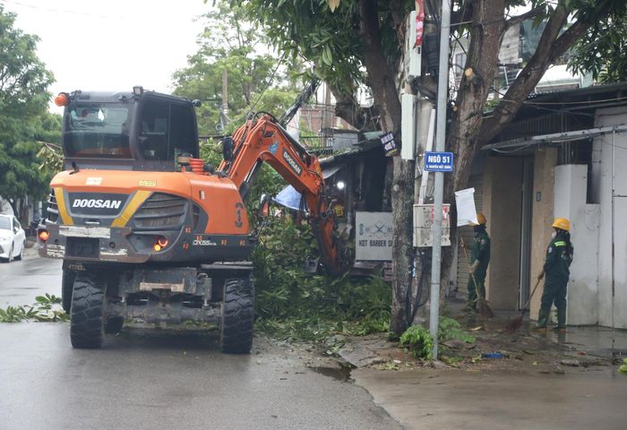 Công nhân tiến hành hốt dọn cành cây xanh bị cắt xuống để khơi thông lòng, lề đường.