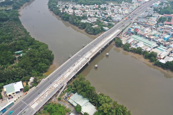 Theo ghi nhận của phóng viên Báo Xây dựng, nhánh cầu Ông Thìn mới (bên trái) nằm cuối tuyến, tiếp giáp tỉnh Tây Ninh, đã được đưa vào sử dụng. Cầu hiện hữu đang được đóng lại để hoàn thiện đường dẫn và gia cường cầu Ông Thìn cũ.