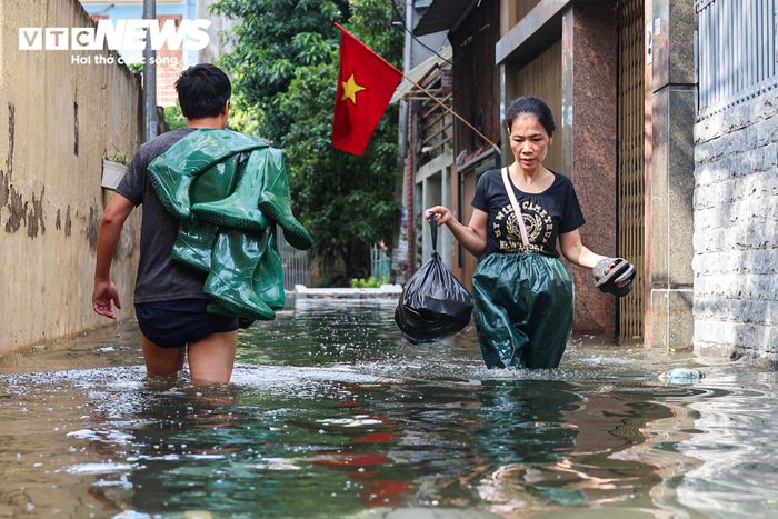 Mực nước ngập sâu khiến việc đi lại trong ngõ gặp nhiều khó khăn.