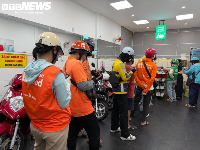 Chị Giang xếp hàng chờ lấy đồ ăn để giao cho khách.