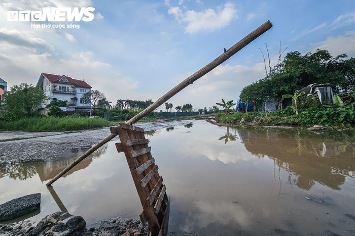 Sau trận mưa lớn 1 ngày, khu vực này vẫn còn ứ đọng nước, mặt đường lầy lội, nhão bùn. Một số thanh gỗ được dựng lên sơ sài bên khu vực cống để cảnh báo người đi đường.