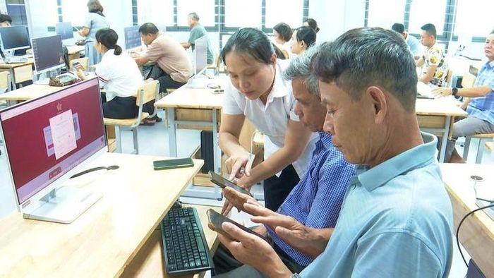 Cán bộ xã trực tiếp hướng dẫn người dân lớn tuổi cách thao tác trên điện thoại thông minh để thực hiện các thủ tục hành chính. Ảnh PV