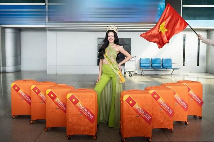 Trước giờ khởi hành, Emoura Phạm thu hút sự chú ý khi diện thiết kế màu xanh nổi bật, đội vương miện và rạng rỡ trước ống kính. Người đẹp giữ thần thái tươi tắn, tràn đầy năng lượng trong ngày lên đường "mang chuông đi đánh xứ người" tại Miss Grand International 2026.
