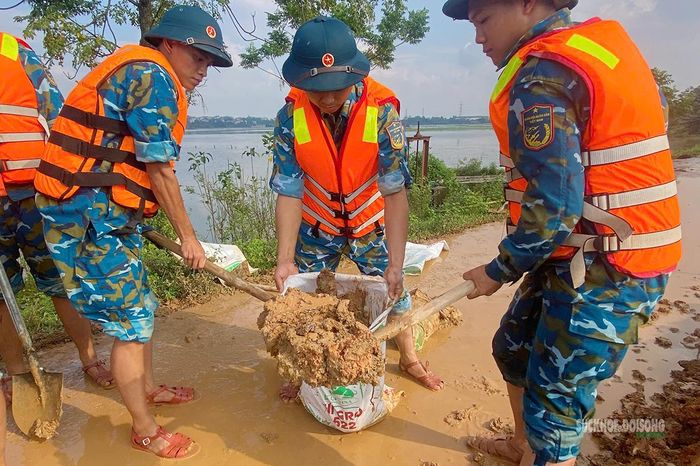 Các chiến sĩ khẩn trương xúc đất, củng cố những vị trí xung yếu trên tuyến đê. Ảnh: H. Thuần