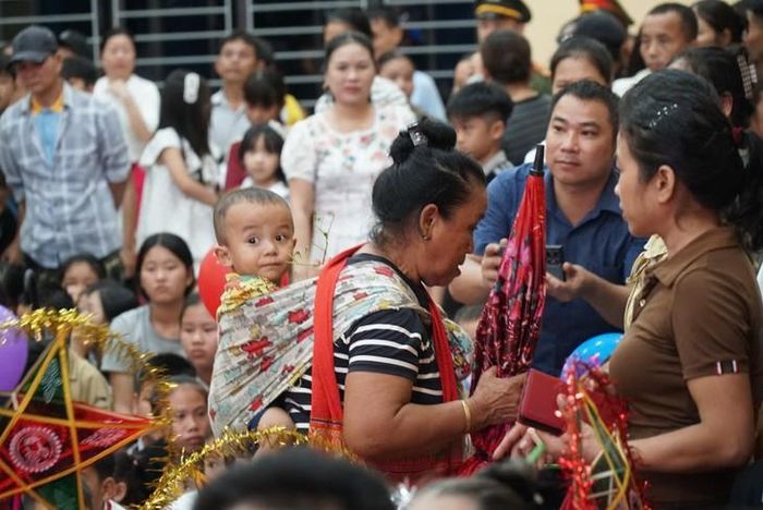 Một phụ huynh đưa con đến tham dự chương trình “Vầng trăng yêu thương”, nhận quà trung thu trong không khí ấm áp, vui tươi. ẢNH: H. Trinh