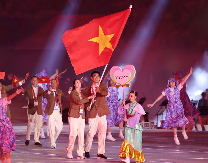 Quang Kiệt và thành viên của đội tuyển bóng chuyền nữ Thanh Thúy cầm cờ diễu hành cho Đoàn Thể thao Việt Nam tại ASIAD 20. Ảnh: Mai Hưng.