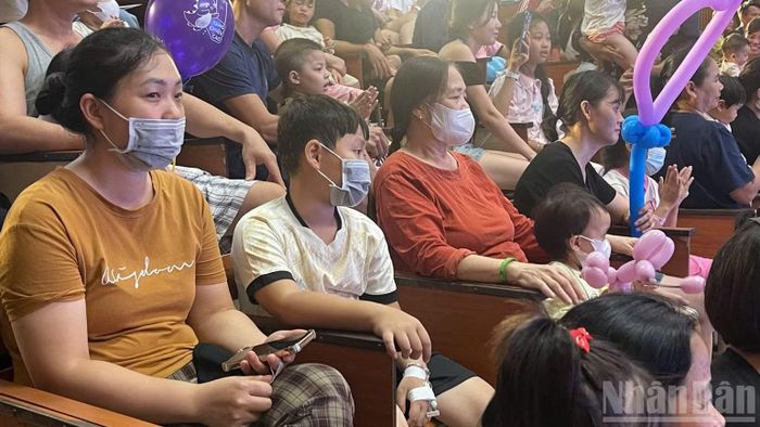 Dù tay còn đeo kim luồn và mệt mỏi do sốt xuất huyết giảm tiểu cầu bé Vũ Anh Q. (Mê Linh, Hà Nội) vẫn cùng mẹ xuống hội trường xem chương trình nghệ thuật.