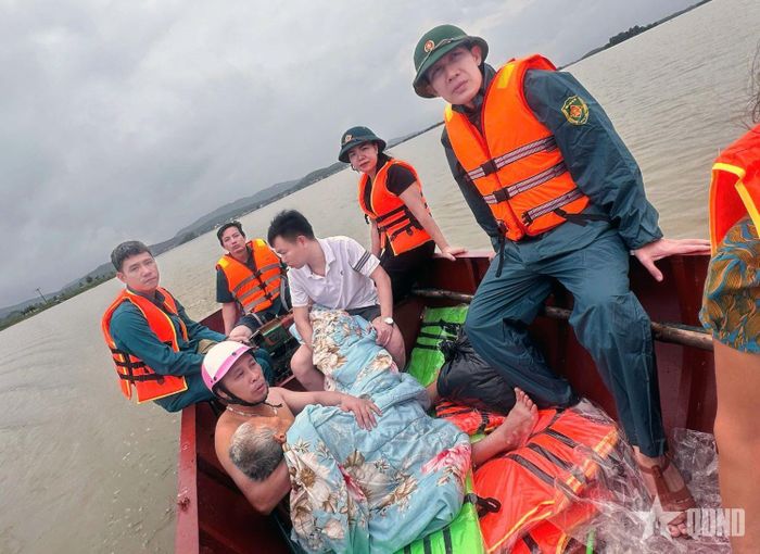 Thượng úy Lê Huy Trường (ngoài cùng, bên phải) cùng tổ cứu nạn, cứu hộ đưa cụ Nguyễn Thị Nhuộm vượt lũ đến bệnh viện cấp cứu. Ảnh: MẠNH HÙNG 