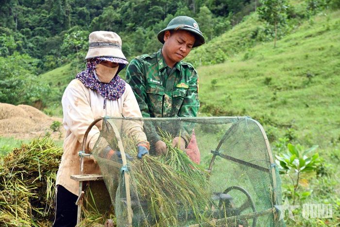 Cán bộ, chiến sĩ và người dân tuốt lúa bằng máy tại điểm tập kết.