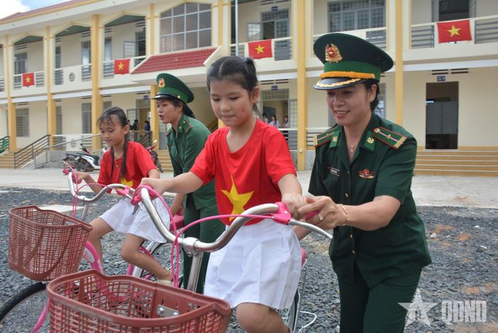 Các em nhỏ được bộ đội hướng dẫn tập đi xe đạp.