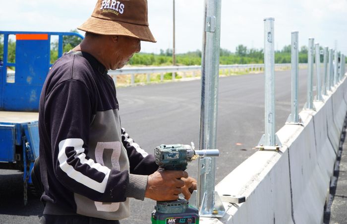  Công nhân các nhà thầu đội nắng thi công lắp đặt rào chắn đường Vành đai 3 qua Đồng Nai. Ảnh: PHÚ NGÂN 