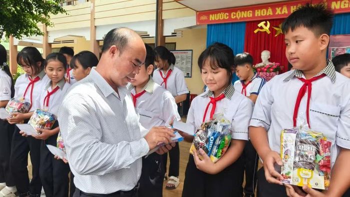 Ông Nguyễn Thế Dương - Chủ tịch Ủy ban MTTQ Việt Nam xã tặng quà cho các em.