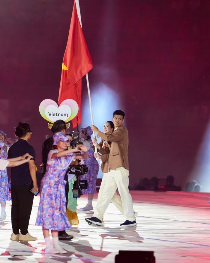 Trung vệ Đinh Quang Kiệt cùng chủ công Lê Thanh Thuý đại diện thể thao Việt Nam cầm cờ lễ khai mạc. Ảnh: Quốc Việt