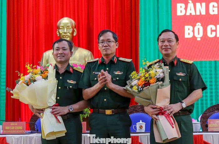 Thiếu tướng Lương Đình Chung tặng hoa chúc mừng đại tá Nguyễn Thế Vinh và đại tá Trần Thế Phan (bên phải) nhận nhiệm vụ mới. Ảnh: Trương Định.