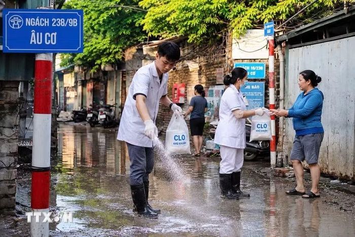 Cán bộ y tế phường Hồng Hà tham gia vệ sinh môi trường cùng người dân. (Ảnh: Kim Anh/TTXVN)