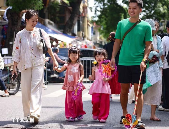Một gia đình vui tươi, rạng rỡ đi chợ Trung Thu truyền thống. (Ảnh: Thanh Tùng/TTXVN)
