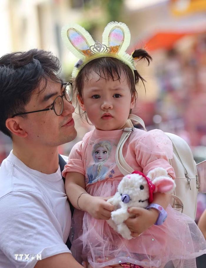 Lần đầu tới chợ Trung Thu truyền thống nên bé vẫn còn nhiều lạ lẫm. (Ảnh: Thanh Tùng/TTXVN)