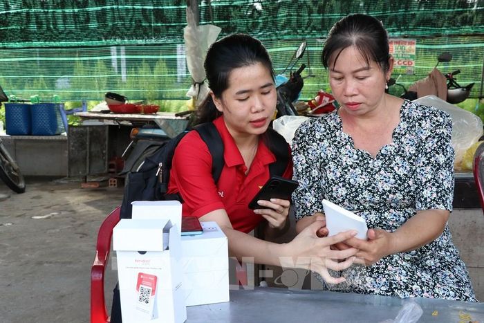 Hướng dẫn tiểu thương chợ Cầu Xây sử dụng bảng mã QR. Ảnh: Thanh Hòa - TTXVN