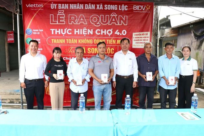 Lãnh đạo địa phương và các đơn vị đồng hành trao bảng mã QR và loa thông báo cho các tiểu thương tại lễ ra quân. Ảnh: Thanh Hòa - TTXVN