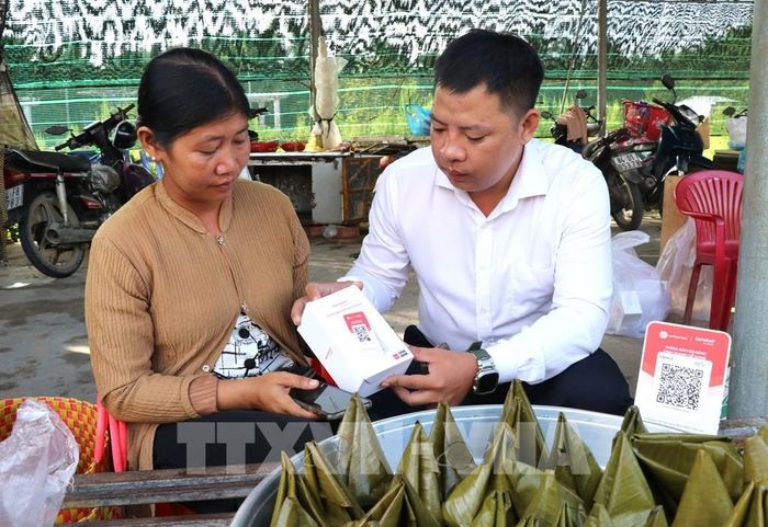 Đại diện Viettel trao và hướng dẫn tiểu thương chợ Cầu Xây sử dụng bảng mã QR. Ảnh: Thanh Hòa - TTXVN