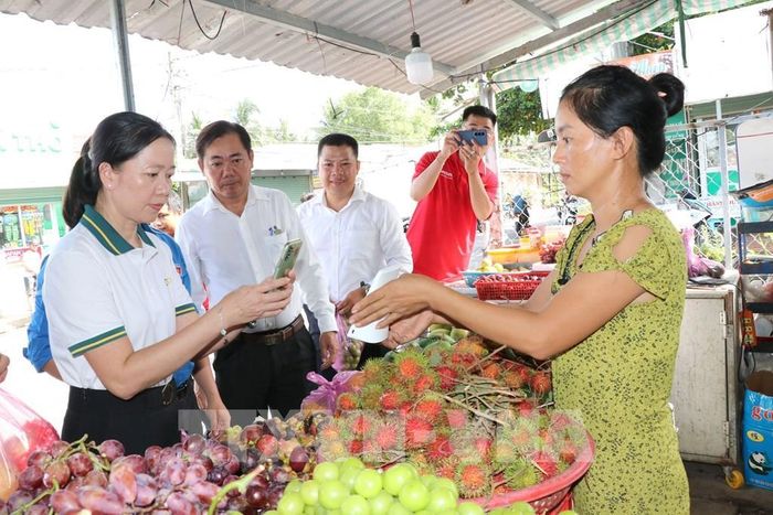 Lãnh đạo địa phương và các đơn vị đồng hành tuyên truyền, hướng dẫn tiểu thương thanh toán không dùng tiền mặt. Ảnh: Thanh Hòa - TTXVN