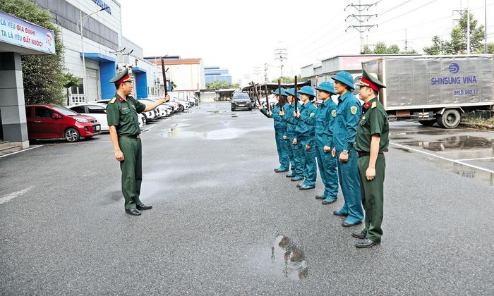 Cán bộ Ban Chỉ huy quân sự phường Tiền Phong hướng dẫn lực lượng tự vệ Công ty Shin Sung Vina sử dụng công cụ hỗ trợ trong bảo đảm an ninh, trật tự.