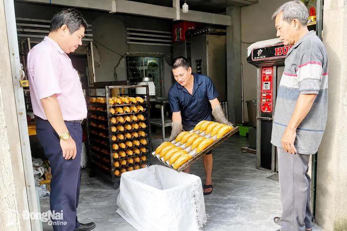 Ông Nguyễn Thế Vinh (bìa trái), Giám đốc Phòng Giao dịch NHCSXH Tân Phú thăm cơ sở sản xuất bánh mì của hộ ông Huỳnh Khang Nam tại khu phố 2, phường Tân Phú, thành phố Đồng Nai. Ảnh: Viết Cường
