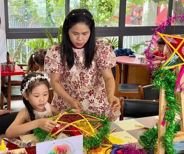  Chị Lê Thị Ái Vy hướng dẫn các bạn nhỏ thực hiện từng công đoạn làm lồng đèn. Ảnh: D.L 