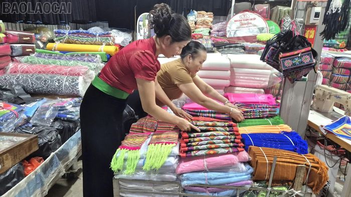 Chị Đinh Thị On (áo đỏ) sắp xếp các mặt hàng khăn Piêu tại gian hàng.