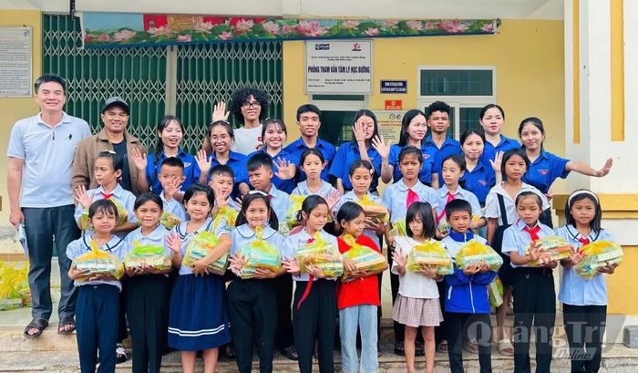 Ka Nụ (áo trắng, đeo kính) trao quà cho các em học sinh Trường tiểu học A Ngo vào đầu tháng 9/2026 - Ảnh: NVCC