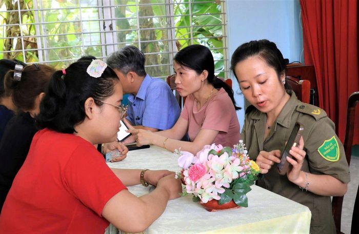 Cán bộ trong Tổ công nghệ số cộng đồng và cán bộ Trung tâm Phục vụ hành chính công đến tận ấp hướng dẫn người dân thực hiện một số TTHC trong mô hình "Công chức gần dân - Dịch vụ công đến tận ấp"