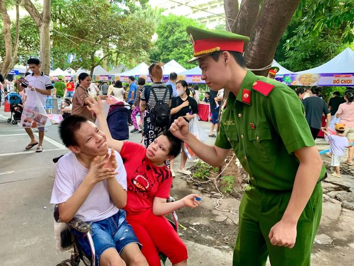 Hai chú bé ngồi xe lăn điều trị nhiều năm tại bệnh viện vui vẻ làm theo hướng dẫn của tình nguyện viên là sinh viên Học viện Cảnh sát nhân dân.