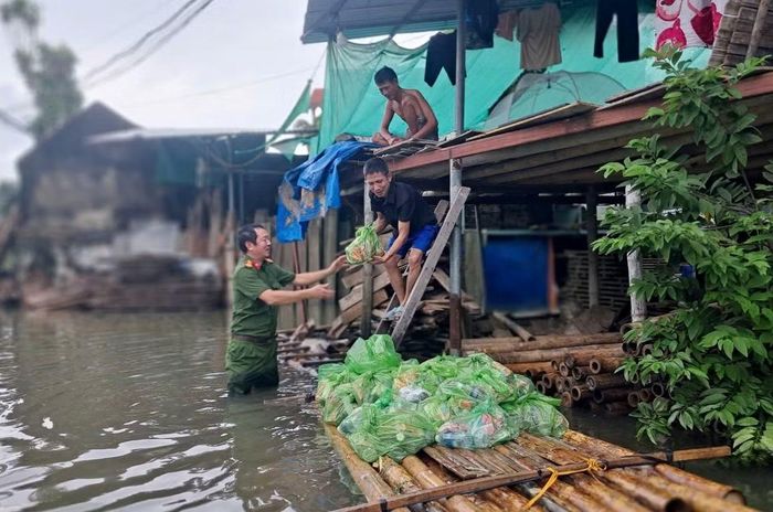 Công an cơ sở hỗ trợ nhu yếu phẩm cho người dân bị ngập lụt.