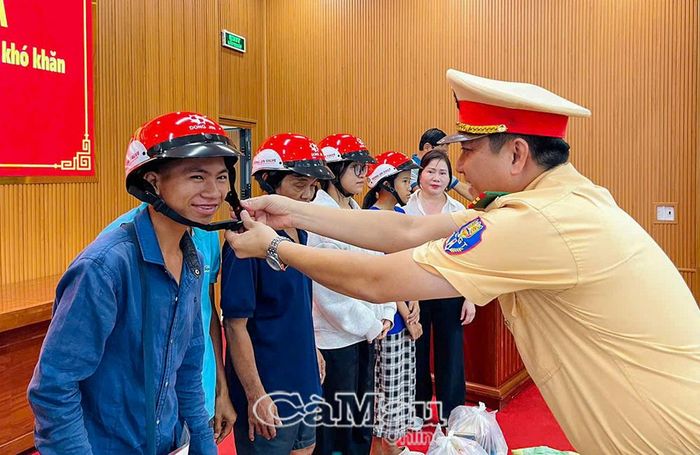 Thiếu tá Nguyễn Quốc Tưởng, Phó Đội trưởng Đội Cảnh sát giao thông đường bộ số 1 (khu vực Cà Mau), trao tặng và hướng dẫn người dân đội nón bảo hiểm đúng cách.