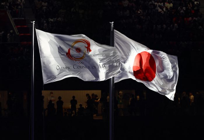 Lá cờ của Hội đồng Olympic châu Á (OCA) được kéo lên cùng quốc kỳ nước chủ nhà trong lễ khai mạc. (Ảnh: Reuters)