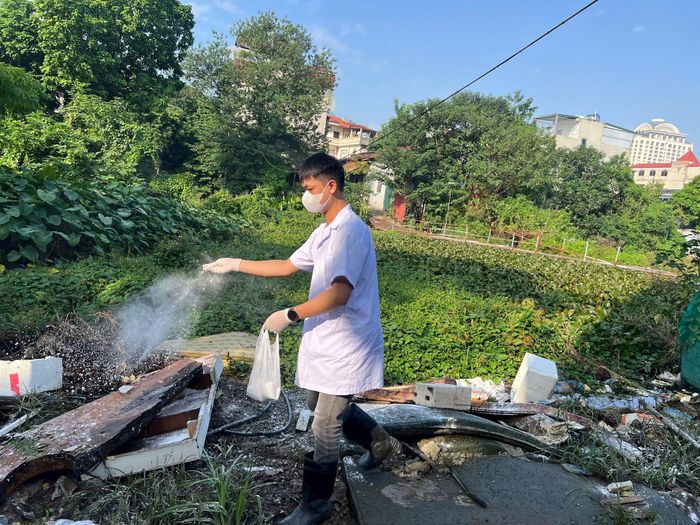 Các nhân viên y tế khử khuẩn tại khu vực công cộng và hướng dẫn người dân tổng vệ sinh môi trường. Ảnh: PHH