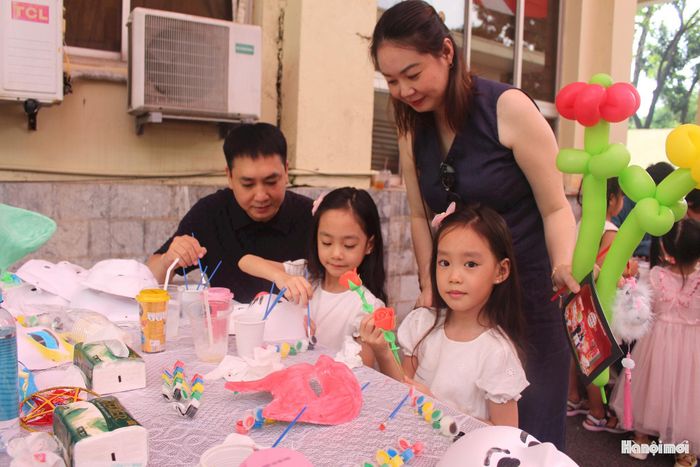 Hai em nhỏ An Vy và An My cùng bố mẹ tô màu mặt nạ Trung thu. Ảnh: Mộc Miên