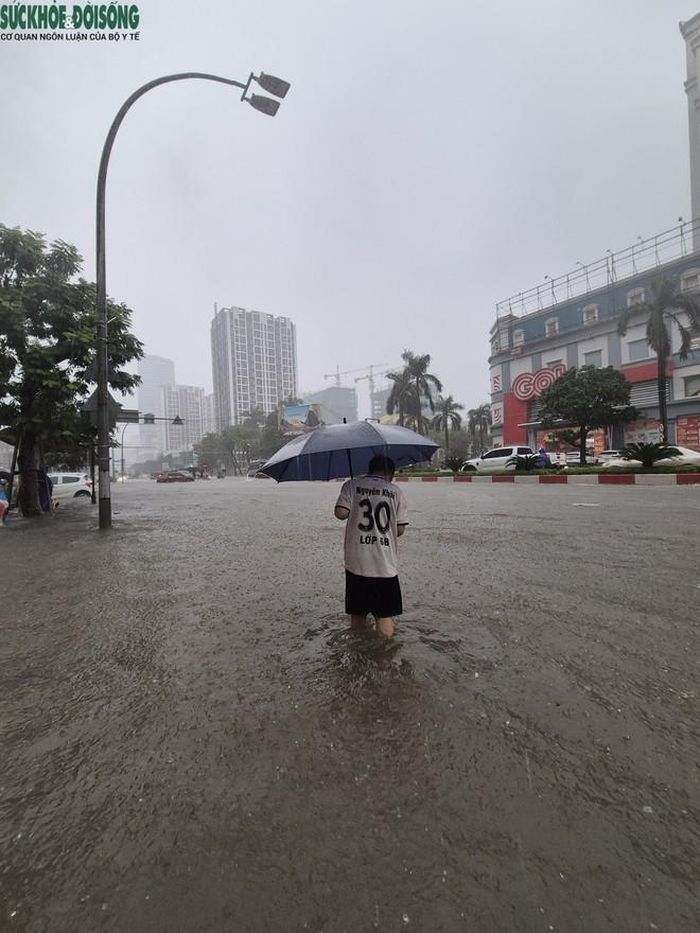 Người dân di chuyển khó khăn khi nước ngập sâu, mưa lớn. Ảnh: V. Đồng