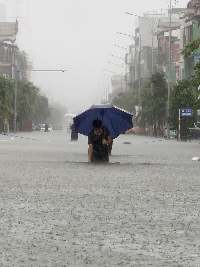 Mưa lớn khiến nhiều tuyến phố ở TP Vinh (cũ) ngập sâu; người dân phải lội nước, trong đó có trường hợp dùng thùng xốp làm phương tiện tạm thời để đưa trẻ nhỏ qua vùng ngập. Ảnh: V. Đồng
