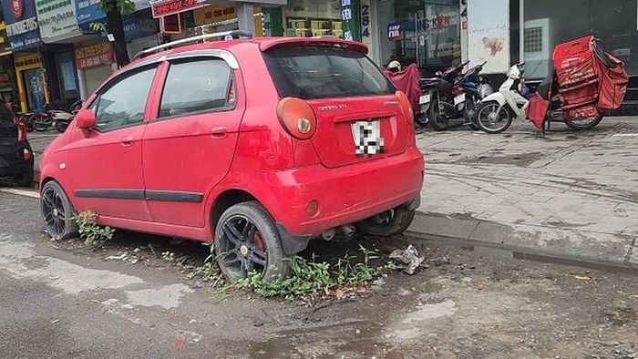 Hình ảnh cỏ mọc hoang dại quanh chiếc xe con tại 282 Xã Đàn. Chị V.T.H. (42 tuổi) làm việc tại khu vực này cho biết, chiếc xe đã nằm cố định ở đây vài tháng. Ảnh: VA.