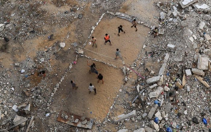 Giữa những tòa nhà đổ nát vì chiến sự ở thành phố Gaza, một nhóm trẻ em Palestine căng lưới chơi bóng chuyền ngày 15/9. Trận bóng nhỏ diễn ra ngay trên khoảng đất phủ đầy gạch đá.