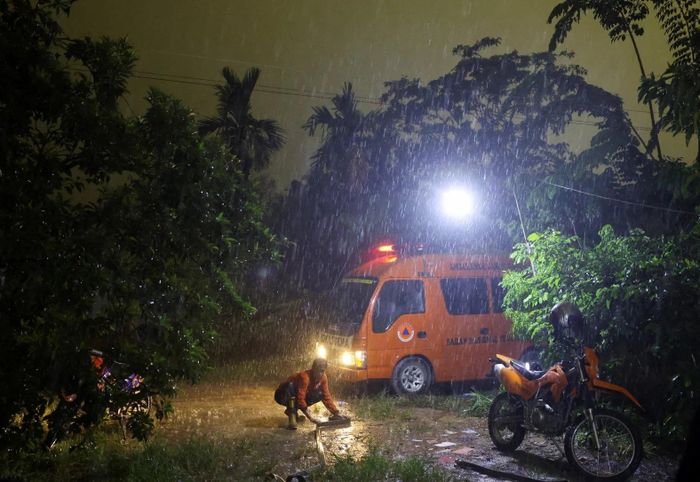Mưa lớn trút xuống Kubu Raya, Indonesia, ngay sau một đợt cháy rừng thiêu đốt vùng đất than bùn. Ngày 15/9, một nhân viên cơ quan ứng phó thảm họa địa phương cuộn lại vòi nước sau khi đám cháy được dập tắt.