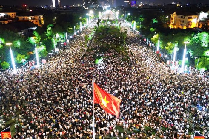 Dù chương trình bắt đầu vào khoảng 20h10, nhiều người đã đến quảng trường từ giữa buổi chiều. Trong thời tiết oi bức, khán giả dùng ô che nắng, ngồi hoặc đứng dọc các khu vực xung quanh sân khấu để chờ đêm diễn. Không khí càng về tối càng sôi động khi dòng người tiếp tục đổ về. Ảnh: Đức Anh.