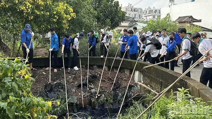 Sinh viên tham gia dọn vệ sinh, khơi thông dòng chảy rạch Nhà Nuôi. (Ảnh: HOÀNG LIÊM)