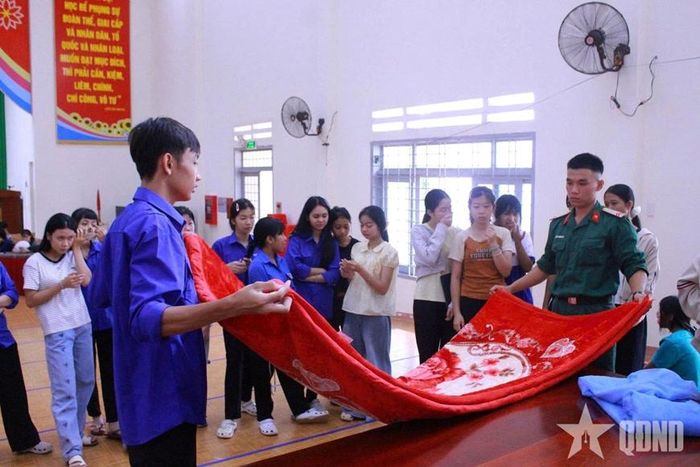  Các em học sinh học cách gấp chăn dưới sự hướng dẫn của chiến sĩ Trung đoàn 584. 