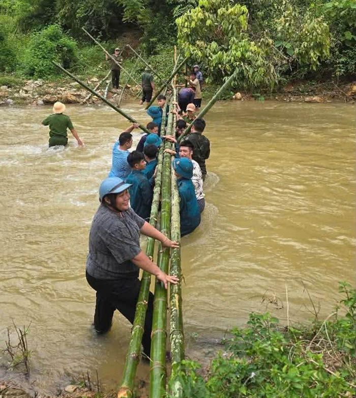 Lực lượng chức năng và người dân dùng tre bắc cầu tạm qua khe