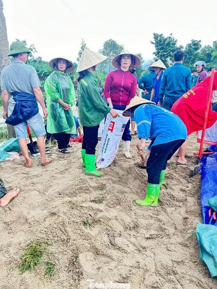  Dưới trời mưa, các lực lượng khẩn trương vận chuyển cát, xúc từng bao để gia cố những vị trí xung yếu. 